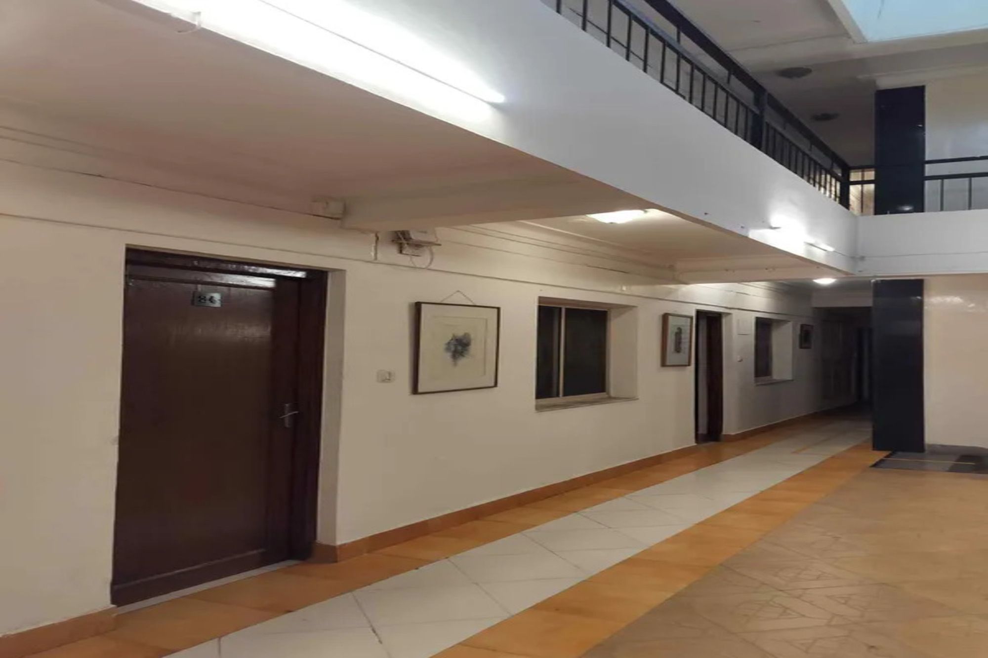 Un pasillo con suelo de madera, paredes blancas e iluminación empotrada en el techo.