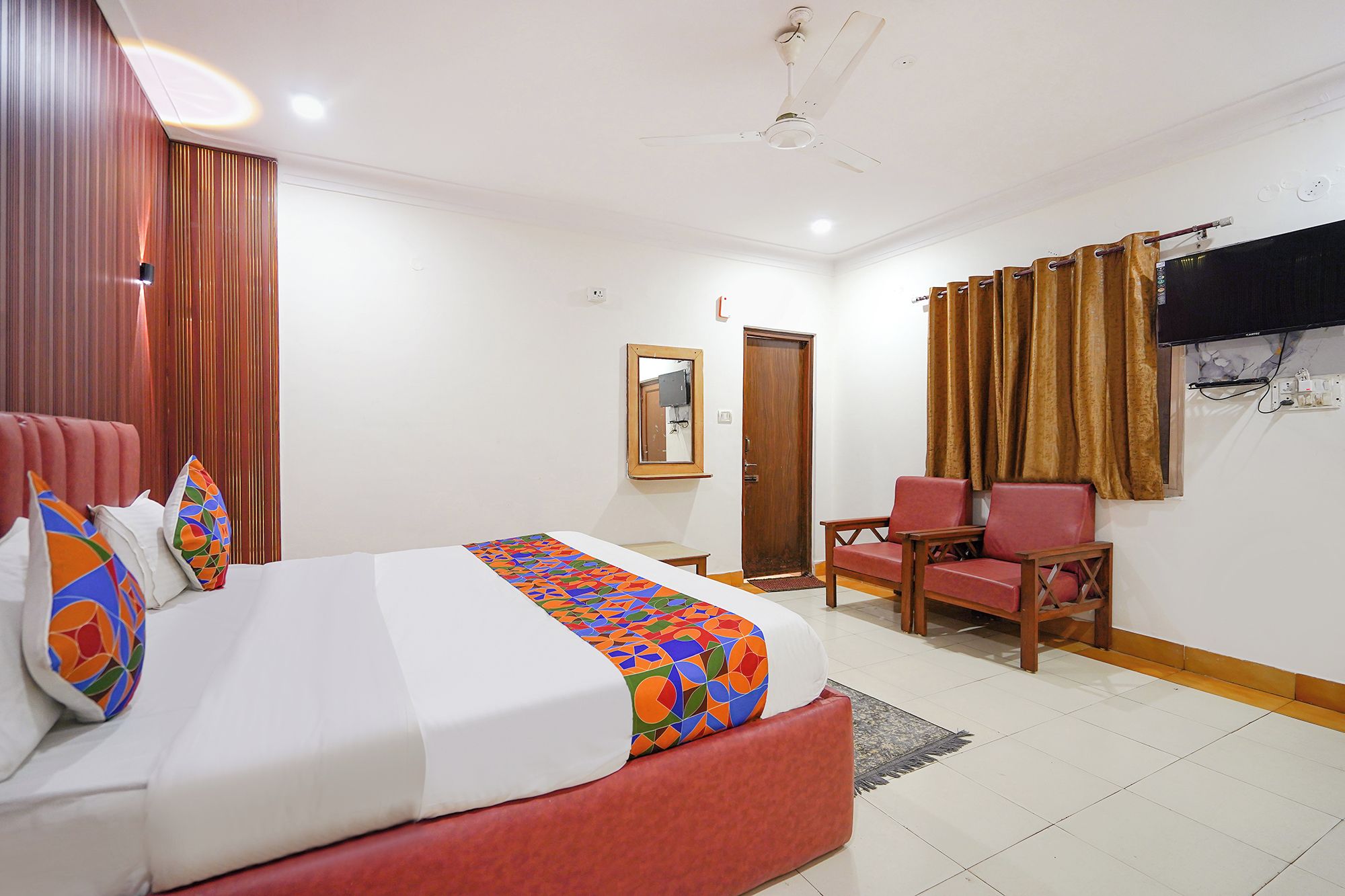 Una habitación de hotel con cama, una silla, televisor y puerta.