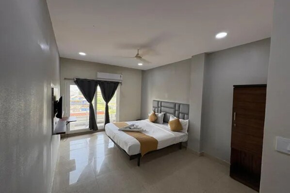 A hotel room with a bed, a ceiling fan, and a door.