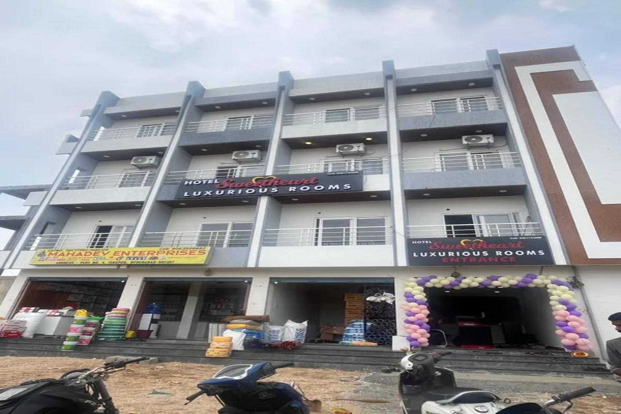 A multi-story building with signs for 'Hotel Sweetheart Luxury Rooms' and 'Mahadev Enterprises.'