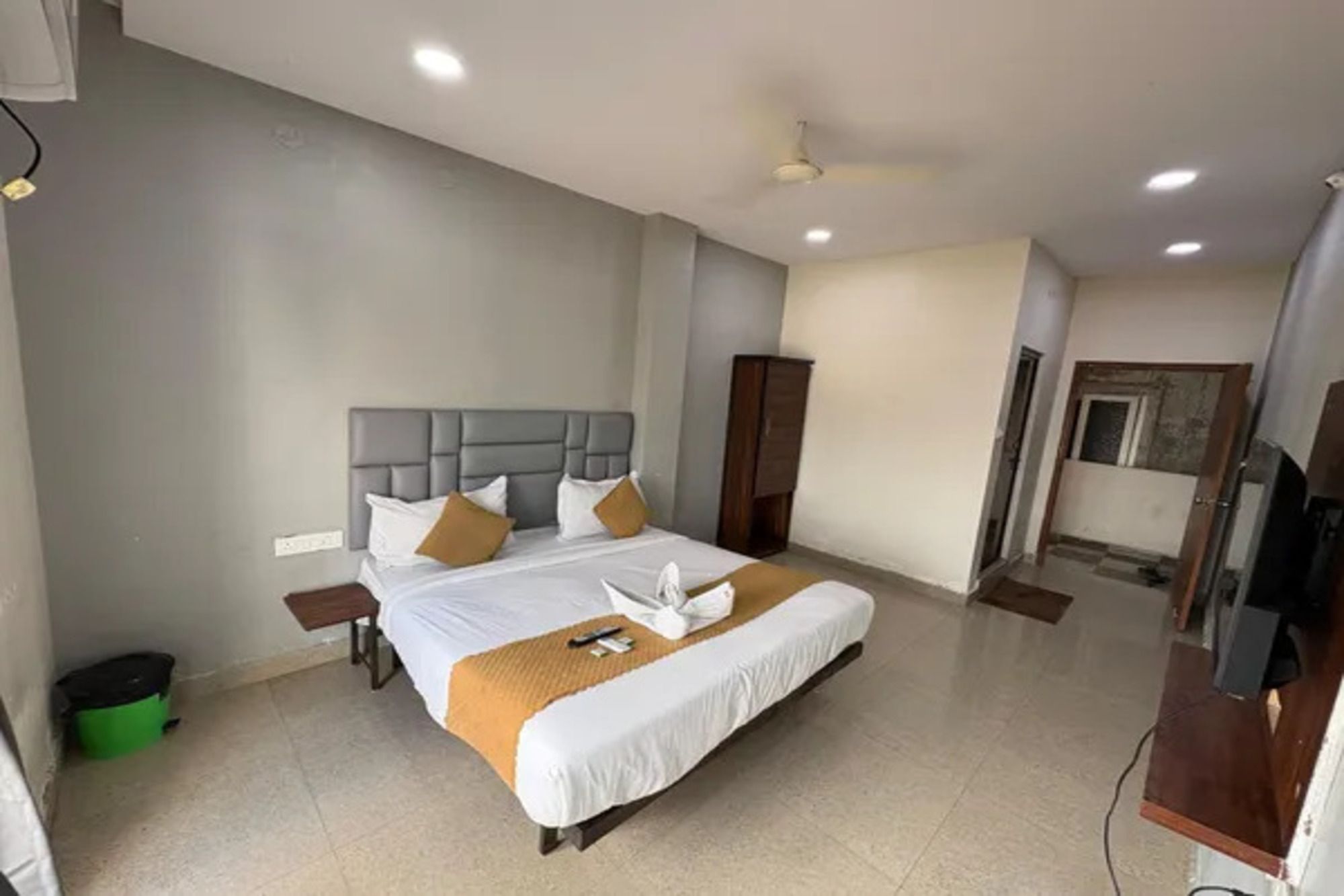 Habitación de hotel con una cama grande, armario, televisor y ventilador de techo.