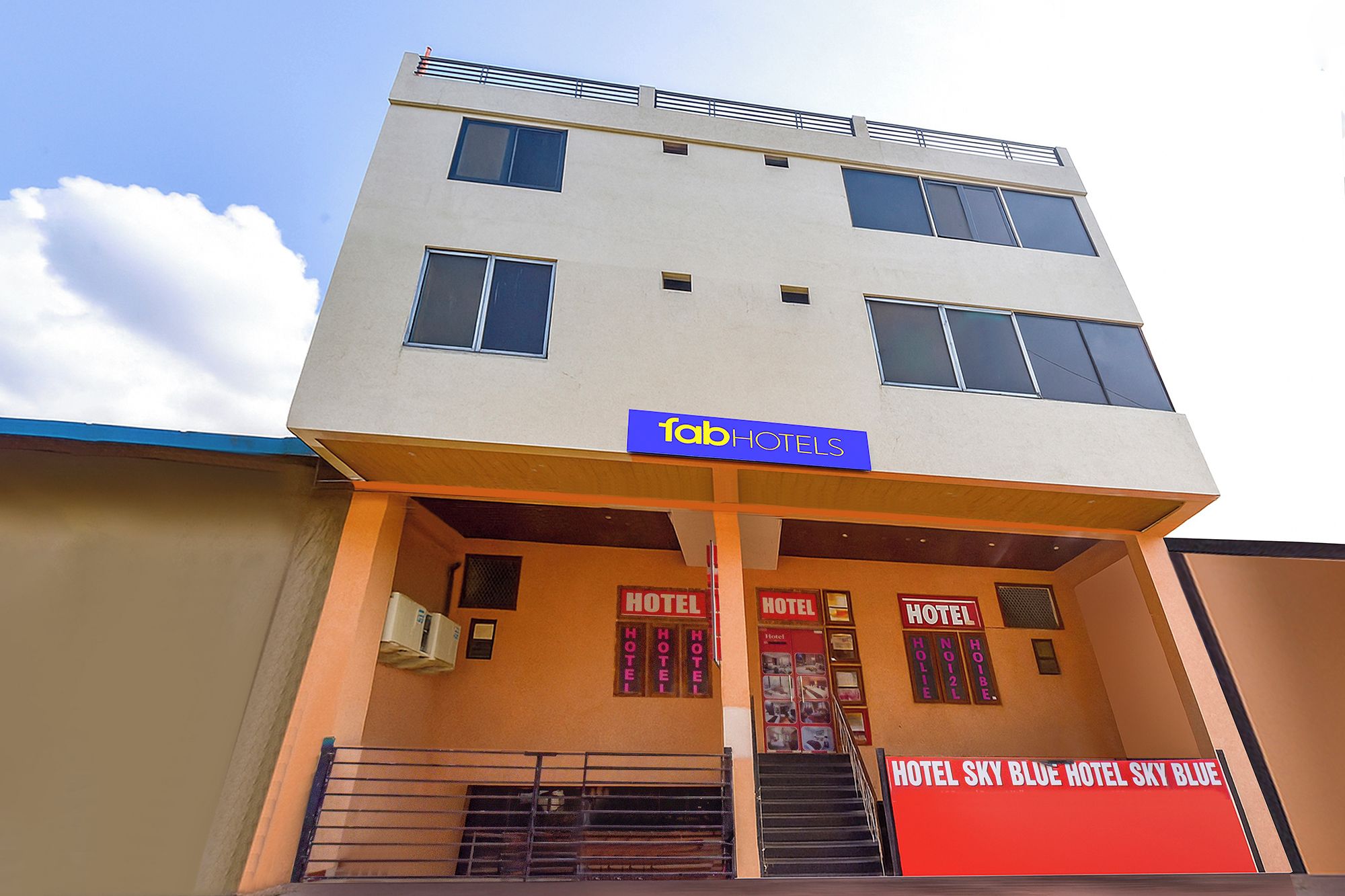 Un edificio de dos pisos con un cartel que dice 'fabHOTELS' sobre la entrada.