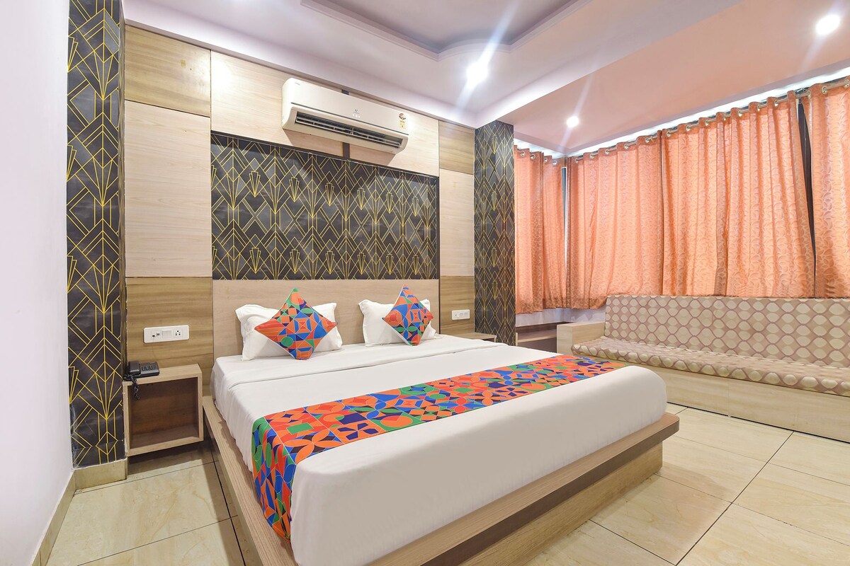 A modern bedroom with a large bed, a sofa, and an air conditioning unit.