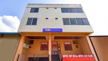 Un hotel de varios pisos con fachada plana, un letrero azul sobre la entrada y múltiples ventanas.