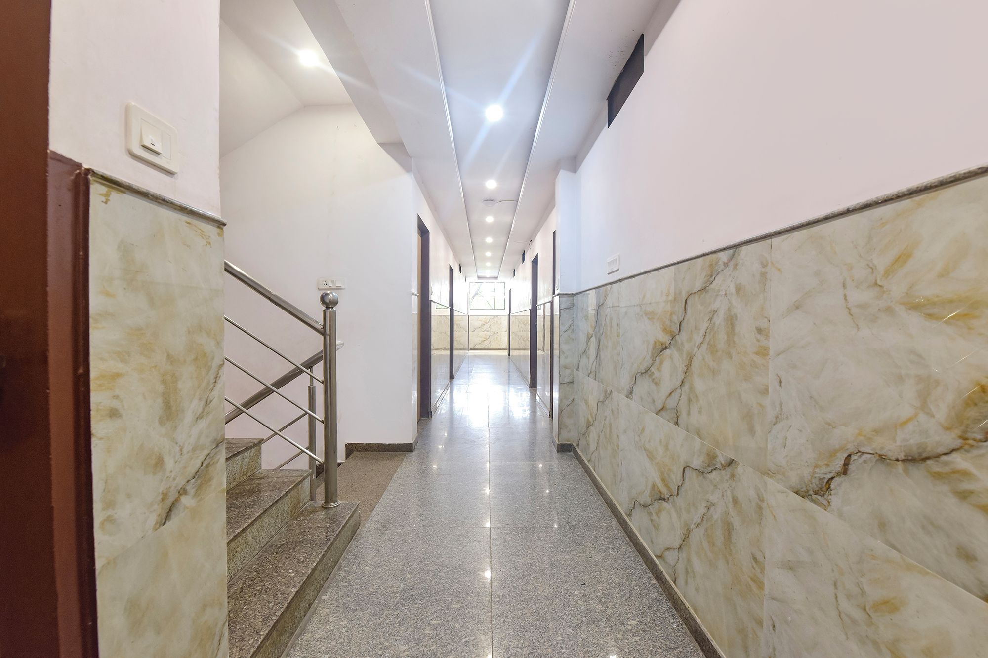 A corridor with marble walls and a metal staircase.