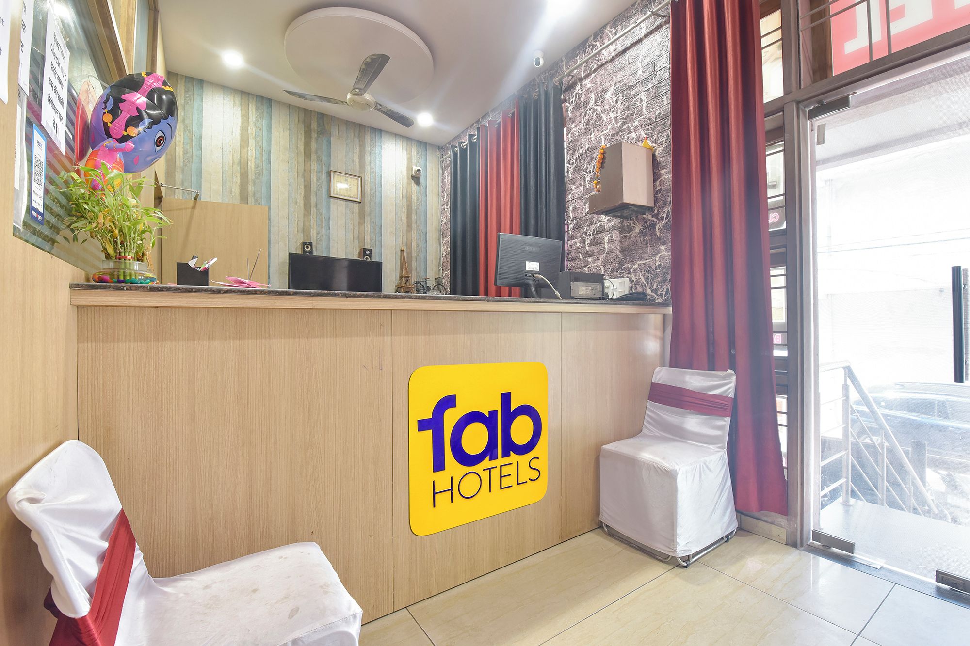 Ein Hotel-Empfangsbereich mit einer Rezeption, einem Computer und einem Schild mit dem Schriftzug 'Tab Hotels'.