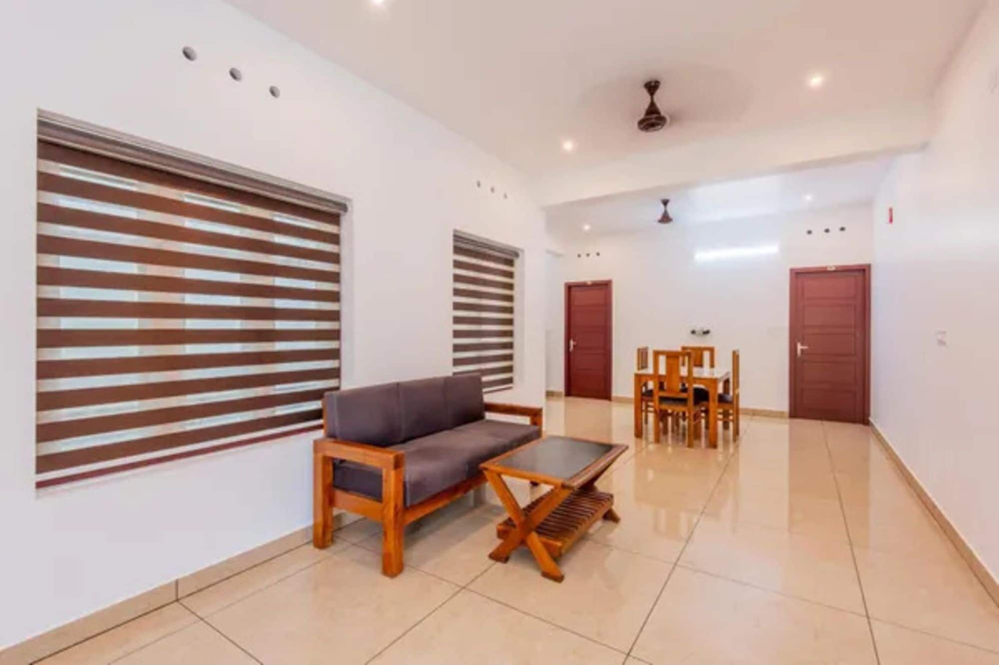 A spacious room with a sofa, a wooden coffee table, and a dining table with chairs.