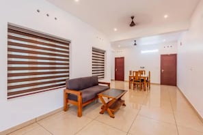 A spacious room with a sofa, a wooden coffee table, and a dining table with chairs. - FabHotel Neo Stayza Elite (Thiruvananthapuram)