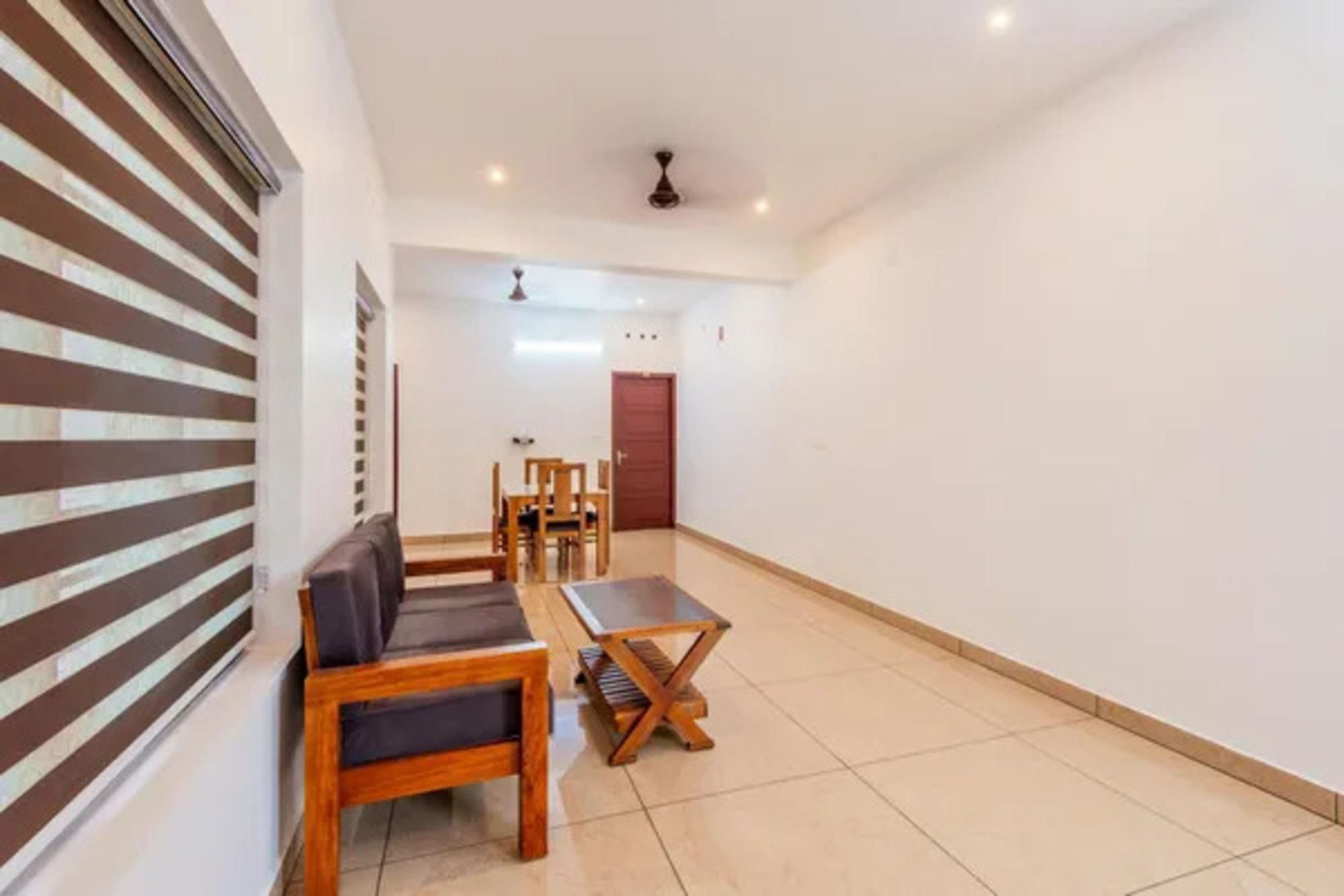 A spacious room with a sofa, a small table, and a dining set.
