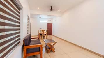 A spacious room with a sofa, a small table, and a dining set.