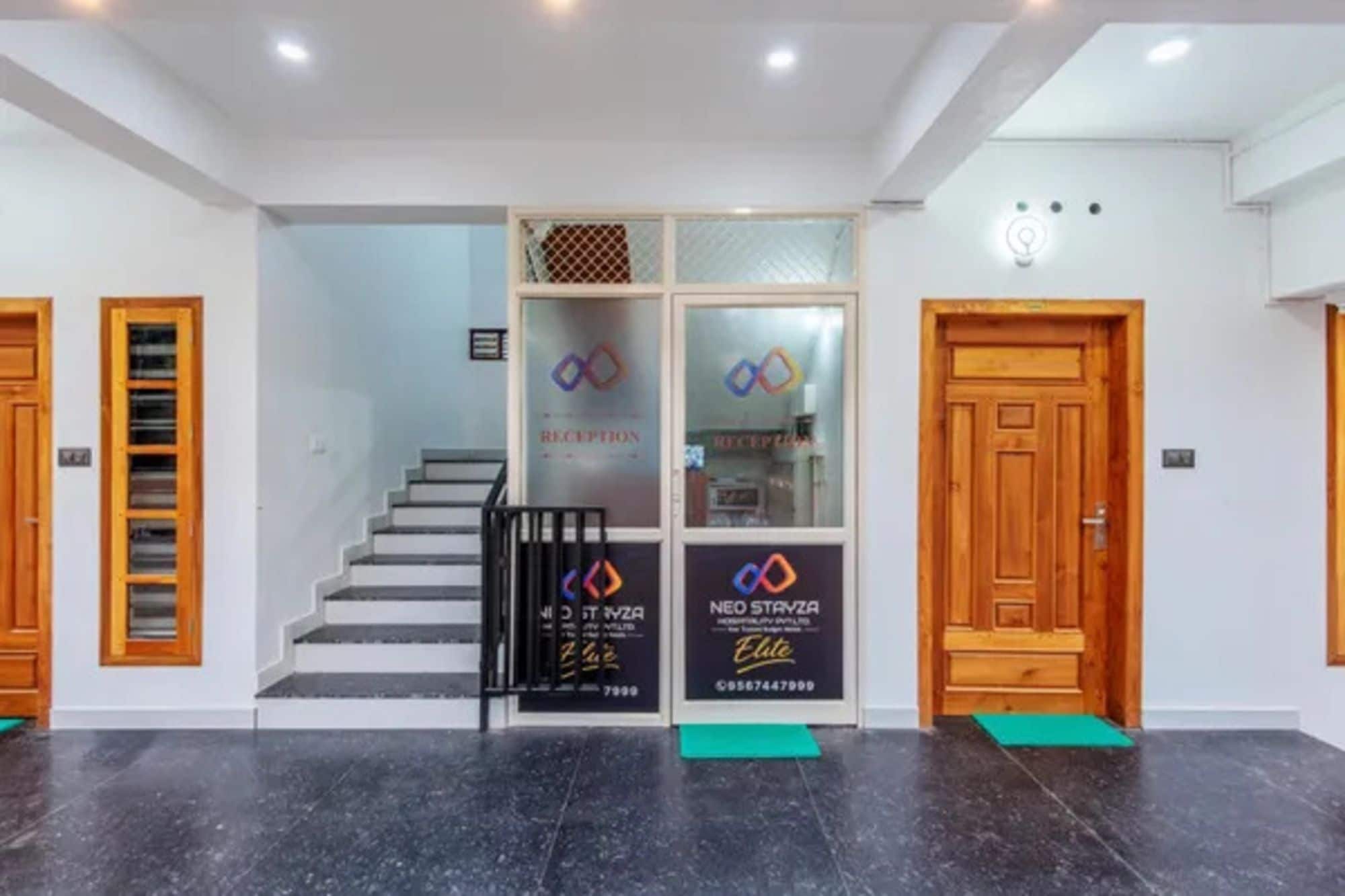 A reception area with a staircase, reception desk, and two wooden doors.