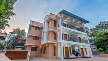 A multi-story residential building with a flat roof, balconies, and a gated entrance.