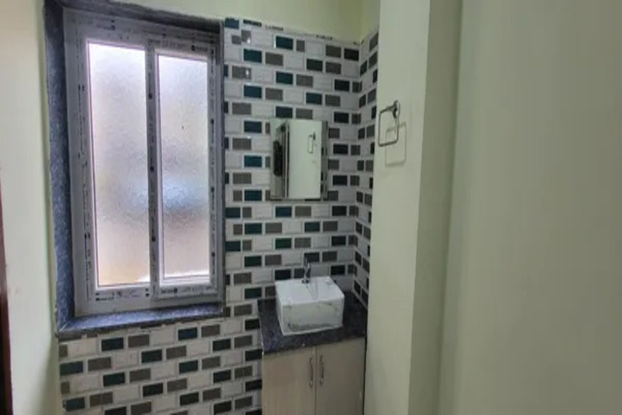 A bathroom with a window, a sink, and a mirror.