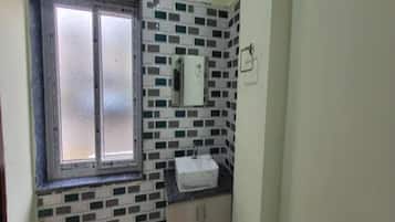 Un baño con ventana, lavamanos y espejo.