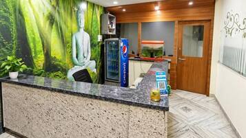 Un espace d’accueil avec une statue de Bouddha, un réfrigérateur de la marque Pepsi et un sol à motifs.