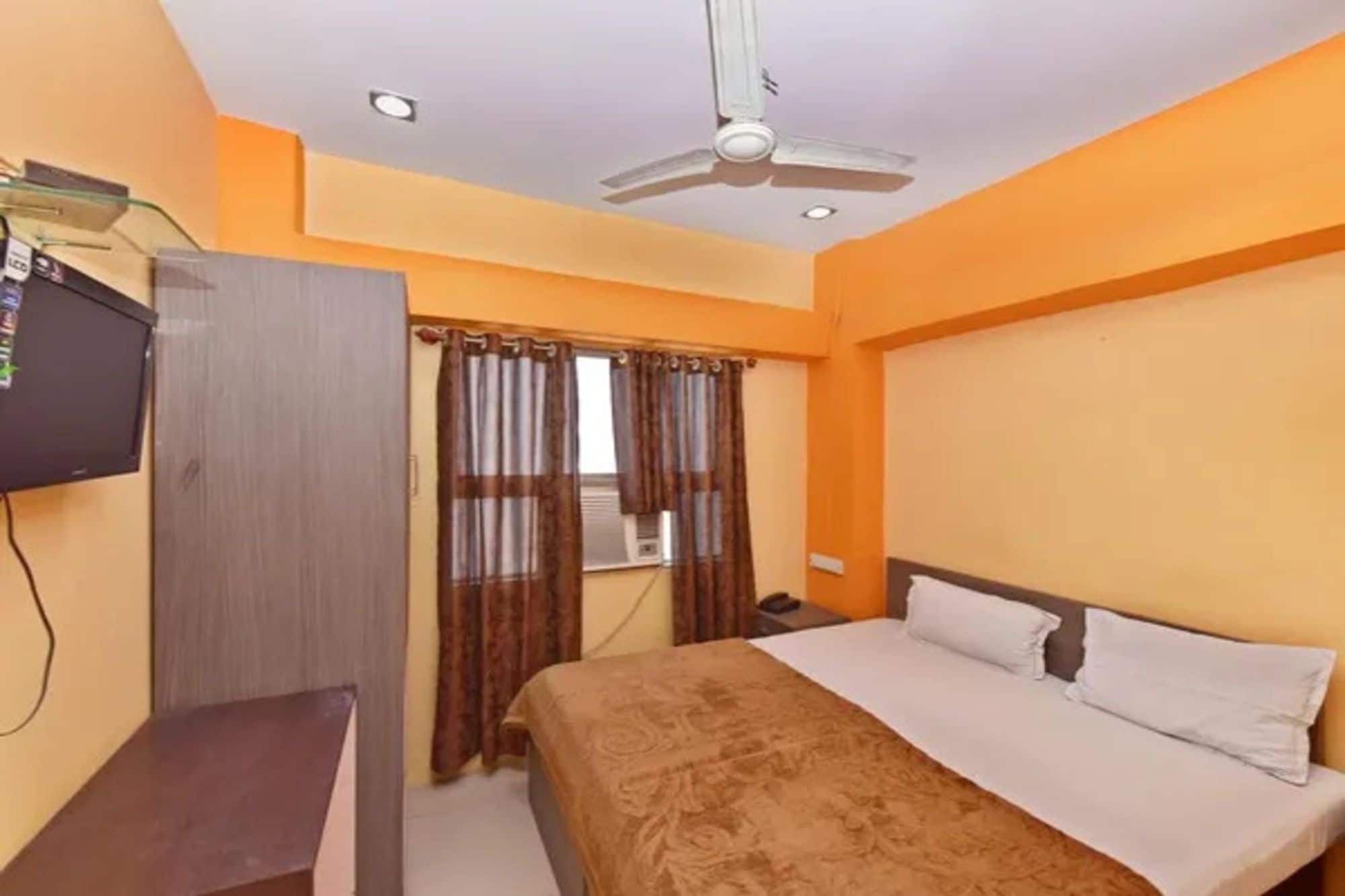 Una habitación de hotel con una cama, un escritorio, un televisor y un ventilador de techo.
