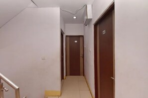 A narrow hallway with a tiled floor, a handrail on the left, and a door at the end. - FabHotel Visawa (Bhopal)