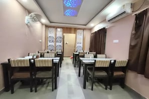 A dining area with a long table and chairs, a ceiling fan, and an air conditioning unit.