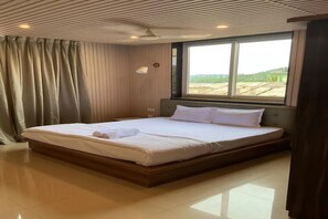 A hotel room with a large bed, a window, and a view of the outdoors.