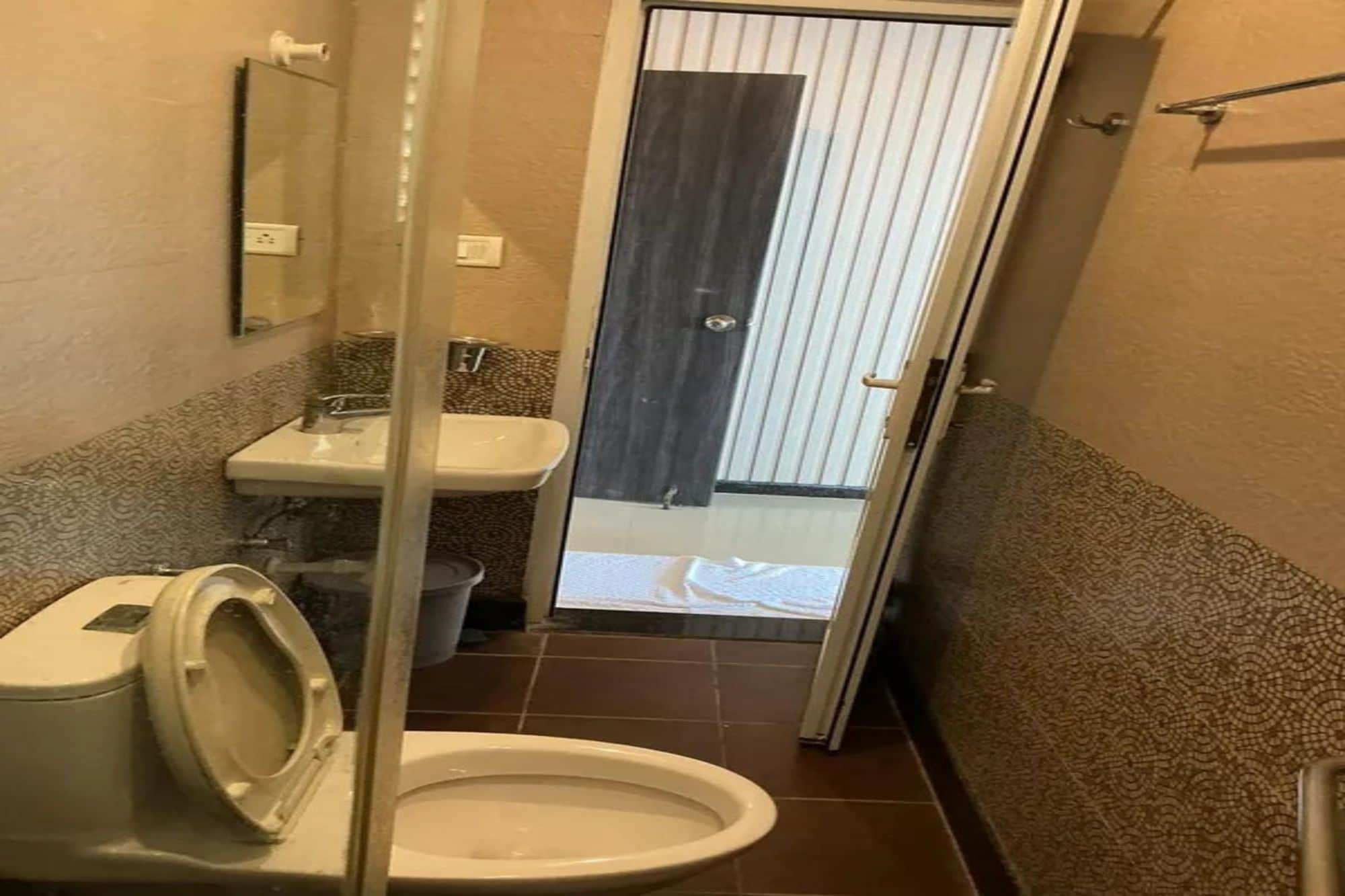 A compact bathroom with a toilet, sink, and a door leading to a balcony.