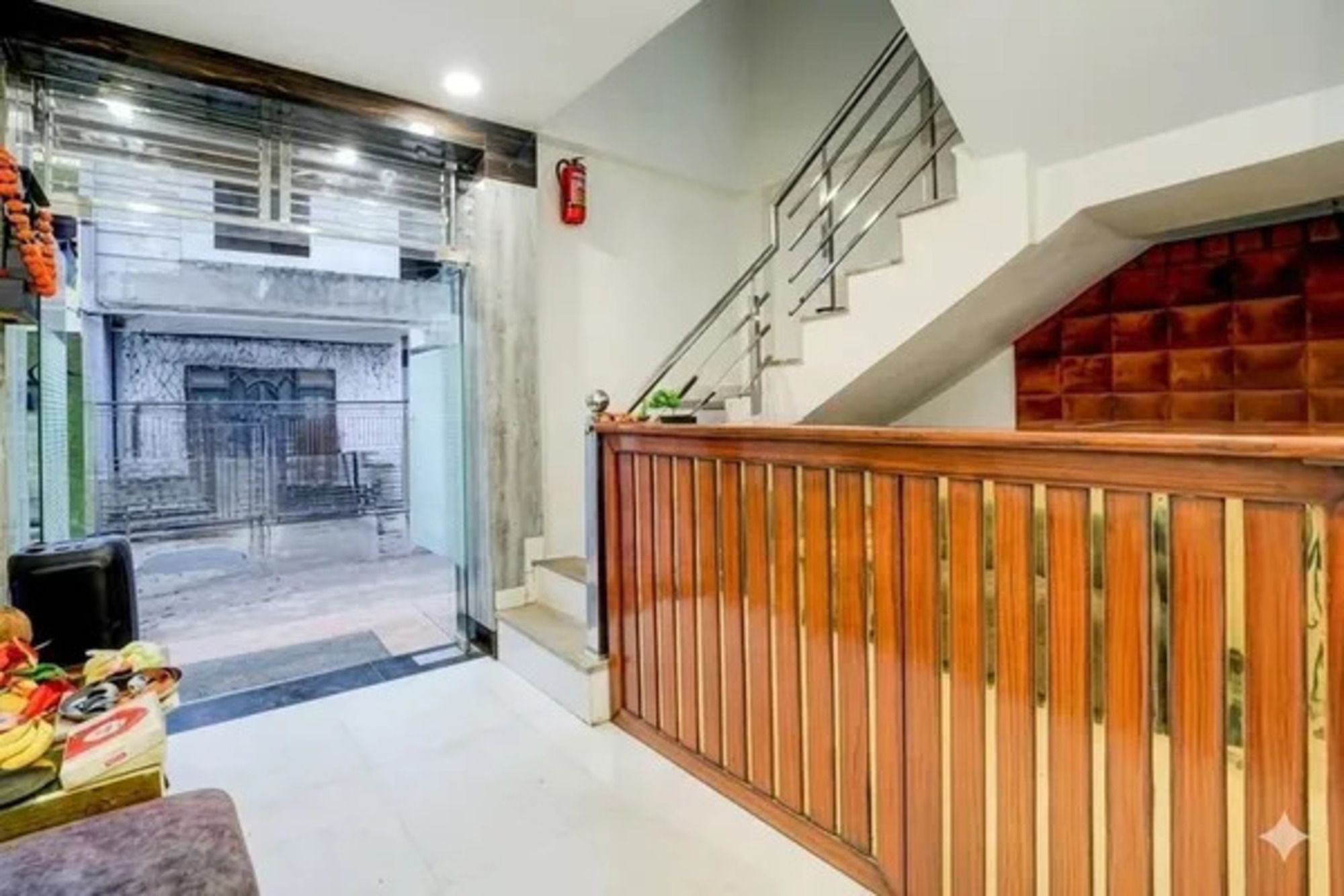 A hotel lobby with a staircase, a fire extinguisher, and a view of the street outside.