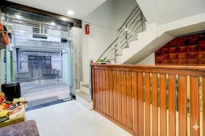 A hotel lobby with a staircase, a fire extinguisher, and a view of the street outside. - FabHotel Trisha'S (Bhopal)