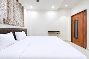 Habitació d'hotel amb un llit gran, una porta de fusta i una petita taula de nit.
