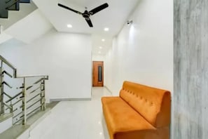 Una escala amb baranes metàl·liques, un ventilador de sostre i una porta de fusta al fons.