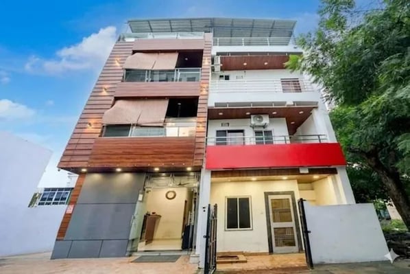 A multi-story building with a flat roof, large windows, and a visible entrance with a door and steps. - FabHotel Trisha'S (Bhopal)