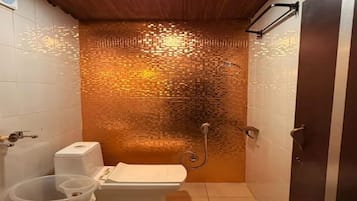 Un baño pequeño con inodoro, ducha y pared con azulejos.