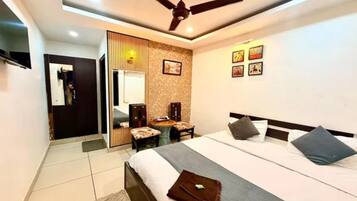Ein Hotelzimmer mit Bett, Schreibtisch, Stuhl, Deckenventilator und einer Wand mit gerahmten Bildern.