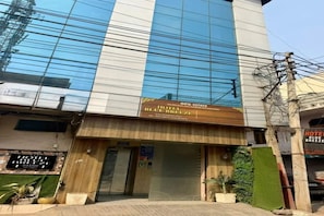 Un hôtel à la façade moderne, une enseigne indiquant « Hôtel Blue Breeze », et une entrée fermée par un portail.