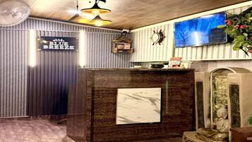 A reception area with a wooden reception desk, a mounted television, and a decorative wall piece.