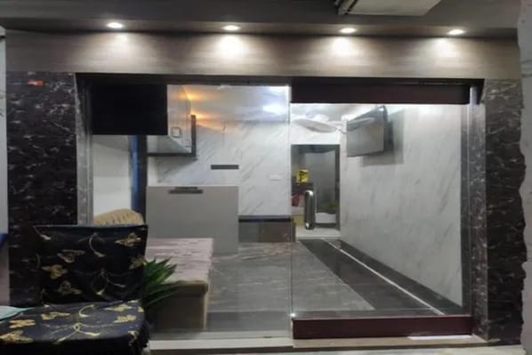 A hotel lobby with a reception desk, a seating area, and a television mounted on the wall. - FabHotel Sr Imperial (Kolkata)