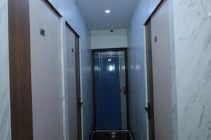 A narrow hallway with a blue door at the end, flanked by walls with a marble-like texture. - FabHotel Sr Imperial (Kolkata)