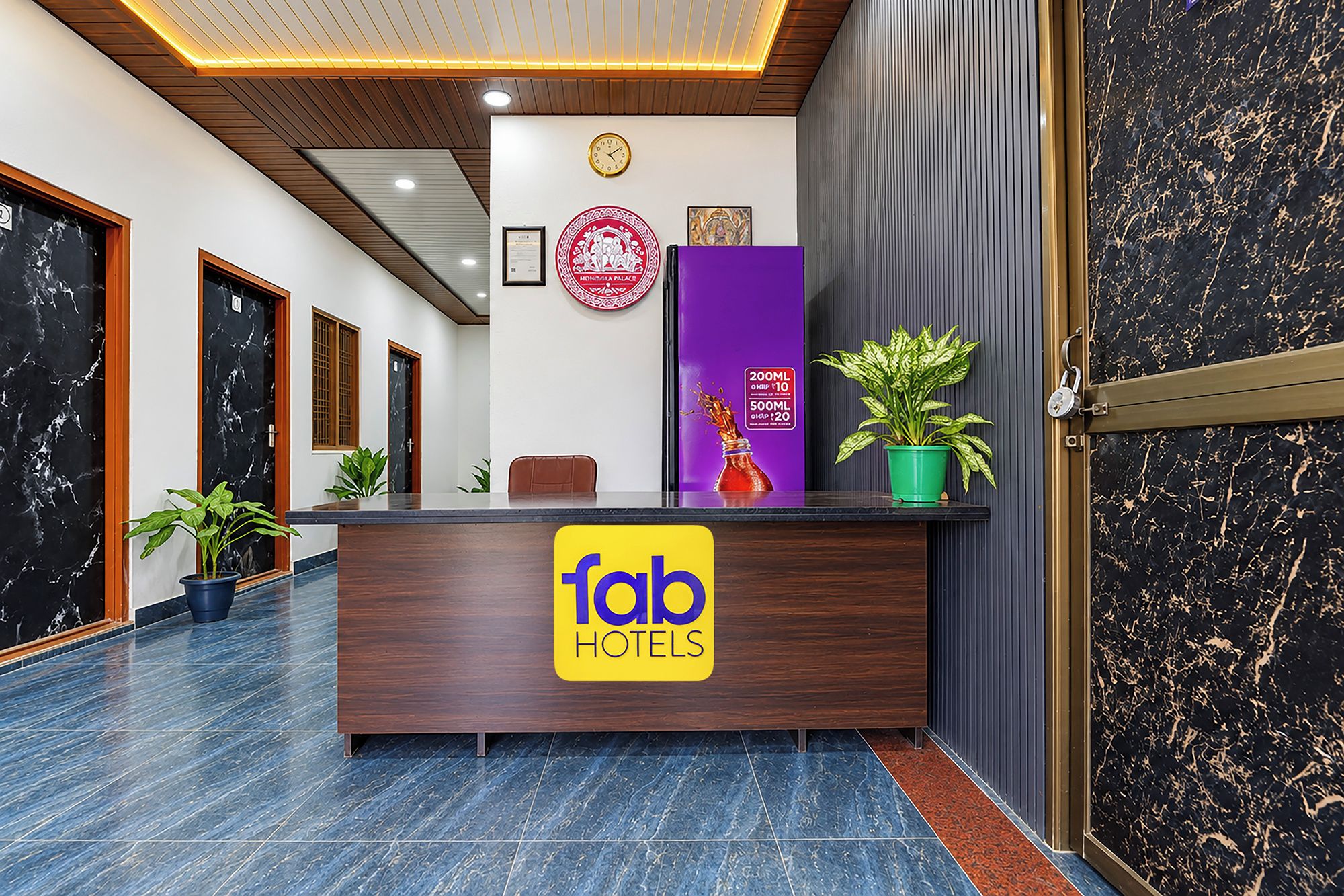 Una mesa de recepción con un cartel que dice 'fab hotels' y un reloj en la pared.