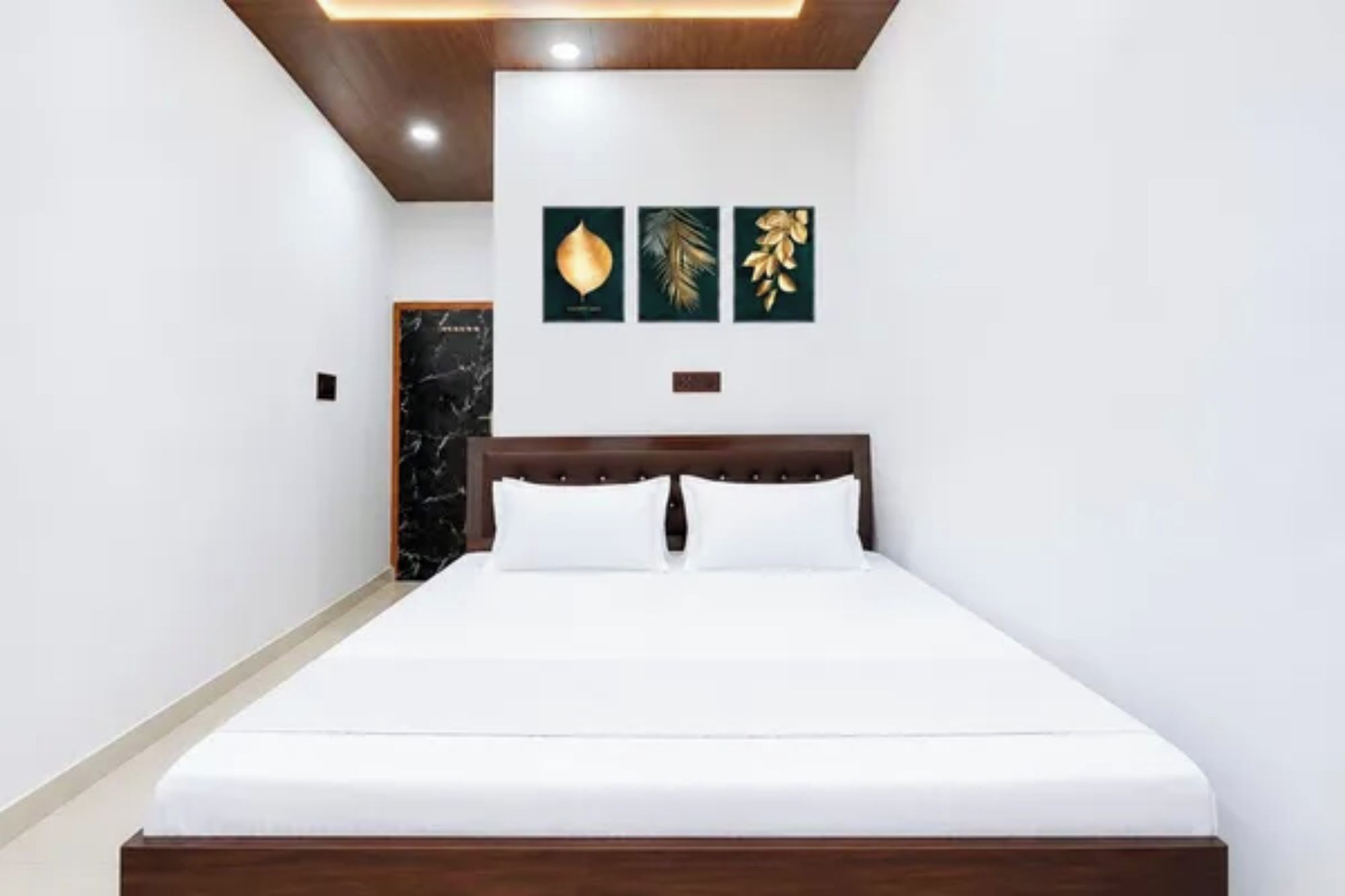 Una habitación de hotel con una cama, cabecera de madera y tres obras de arte colgadas en la pared.