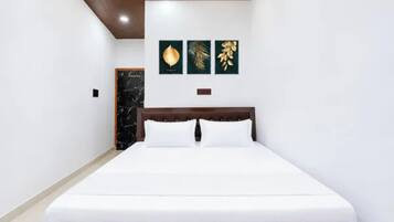 Una habitación de hotel con una cama, cabecera de madera y tres obras de arte colgadas en la pared.