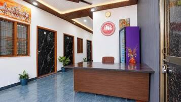 Zona de recepció amb sòl de marbre, taulell de fusta i una paret amb un rellotge i obres d'art.