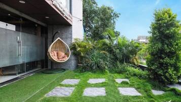 A modern building with a hanging chair, a well-maintained lawn, and stone stepping stones.