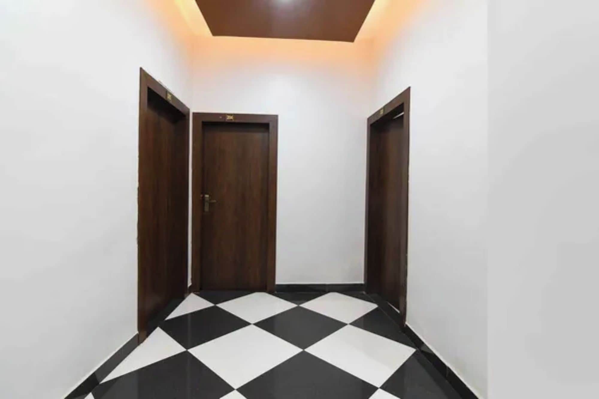A hallway with a checkered floor, a wooden door, and a ceiling light fixture.