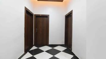 A hallway with a checkered floor, a wooden door, and a ceiling light fixture.