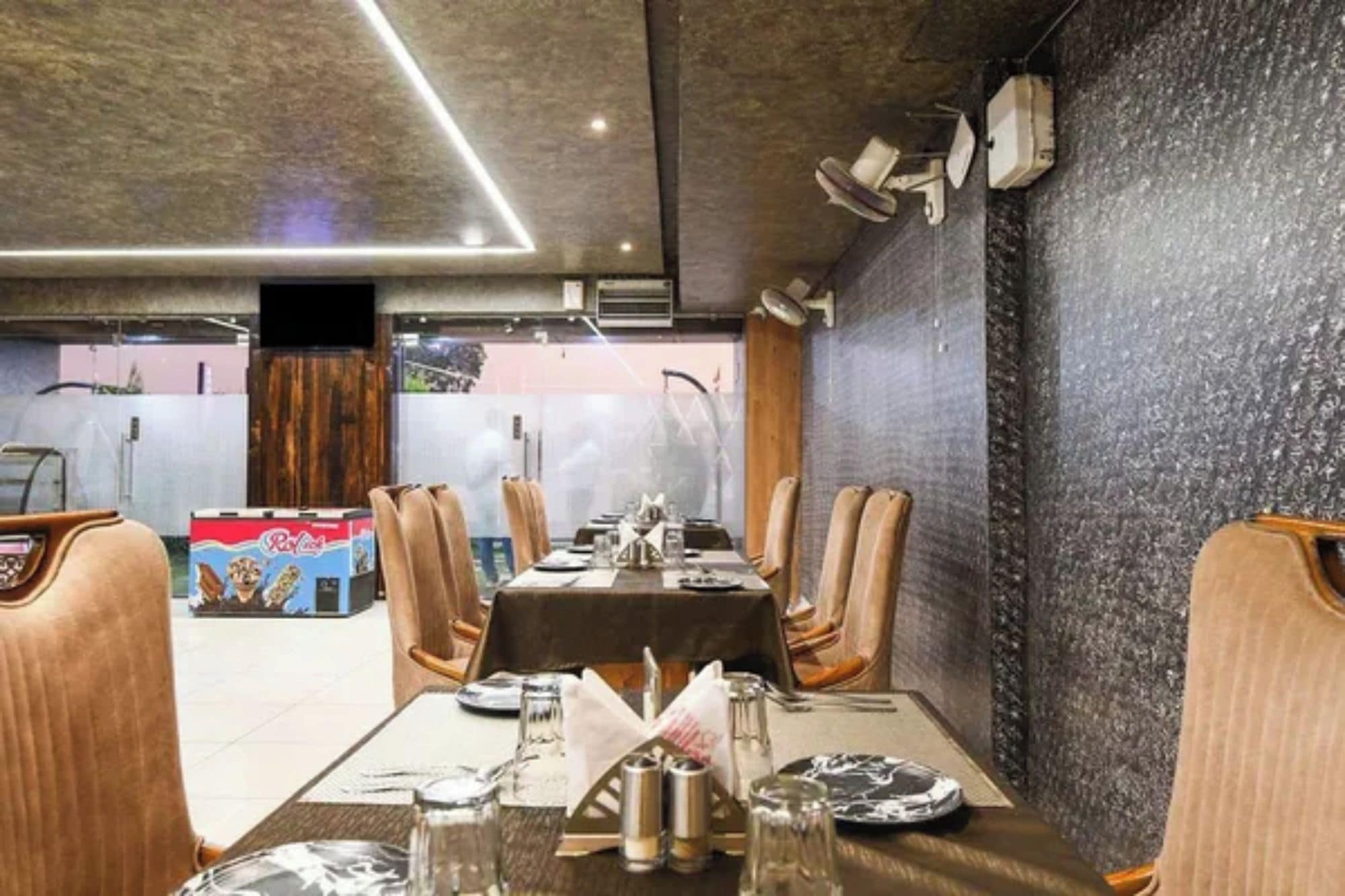 A restaurant interior with a long dining table, chairs, and a stone wall.