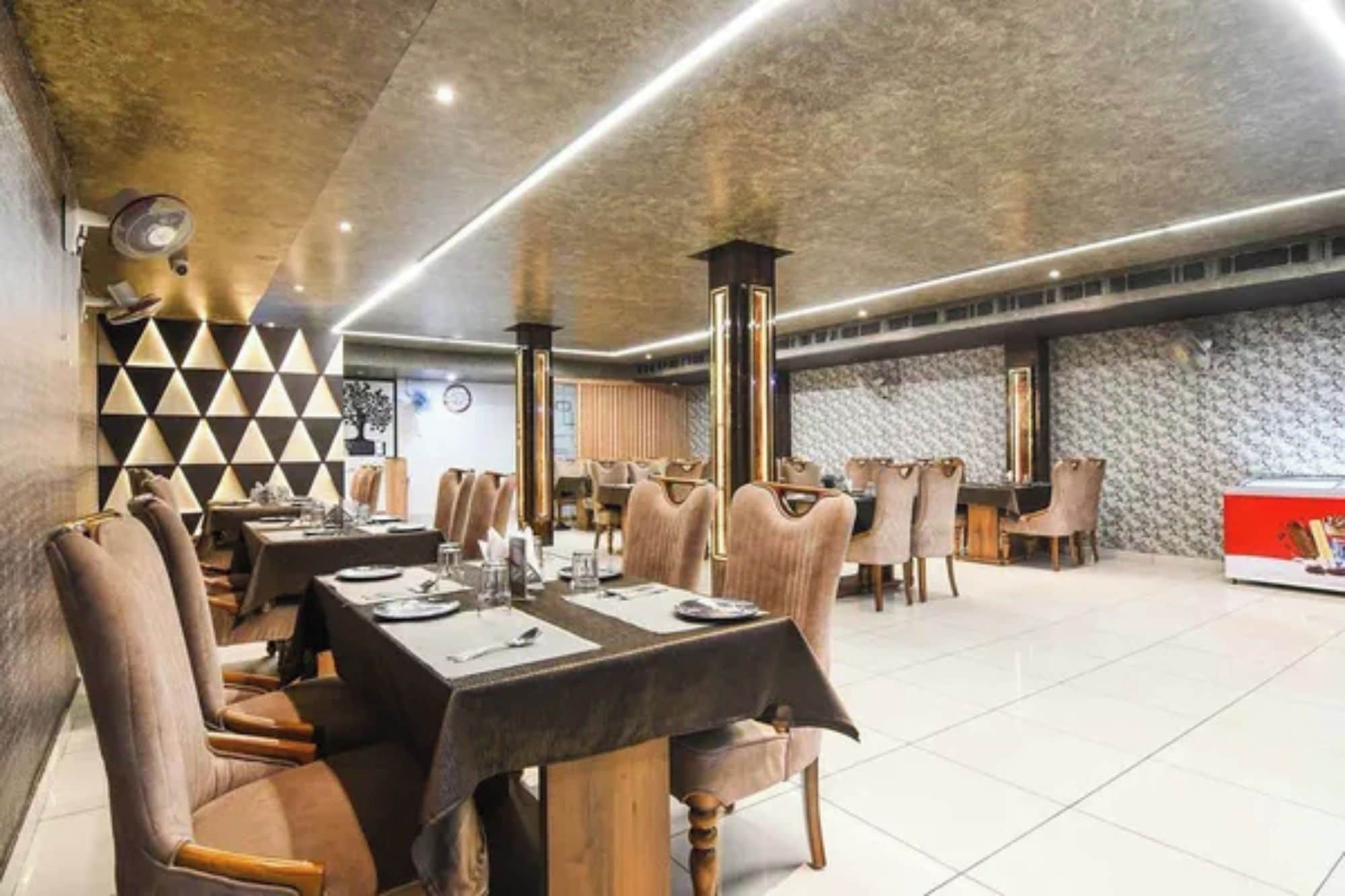 Un restaurante con varias mesas y sillas, un muro con diseño y un techo de estilo moderno.