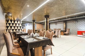 Un restaurante con varias mesas y sillas, un muro con diseño y un techo de estilo moderno.