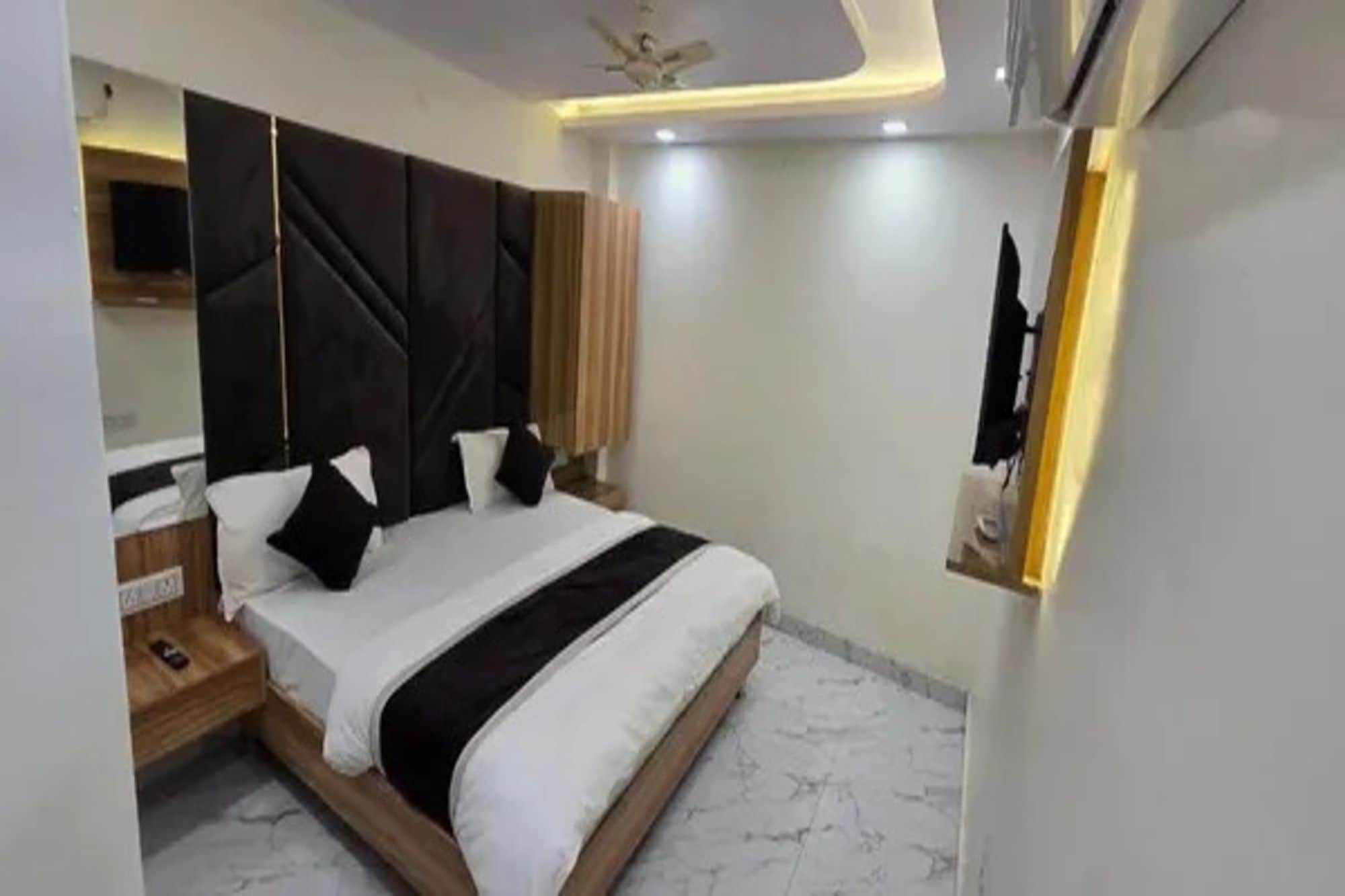 A modern bedroom with a large bed, a bedside table, a wardrobe, and a ceiling fan.