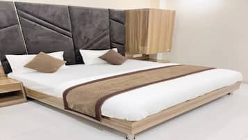 A modern bedroom with a large bed, headboard, bedside tables, and a wardrobe.