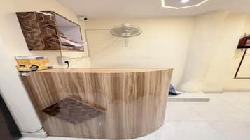 A reception desk with a modern design, a ceiling fan, and a hexagonal light fixture.