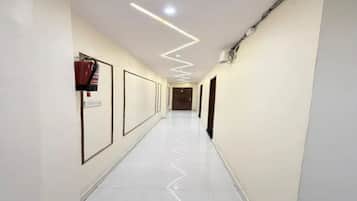 A hallway with a zigzag light pattern on the ceiling, a fire extinguisher mounted on the wall, and a door at the end.