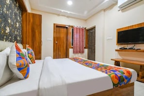 A hotel room with a bed, a television, and a wooden wardrobe. - FabHotel Royal Palace Ab Road (Indore)